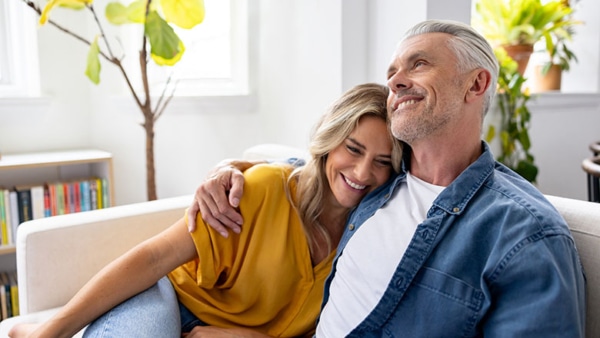 Loving couple spending time together and relaxing at home while smiling on the couch - relationship concepts