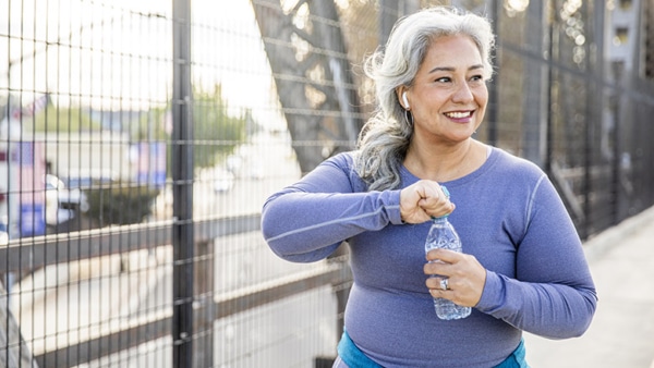 A senior Mexican woman drinking water after a workout