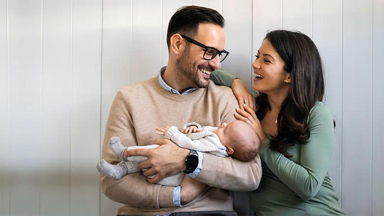 Portrait of parents and newborn baby. Father and mother kiss and hug a beautiful newborn child. .