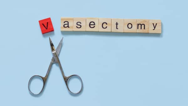 Scrabble letters spelling out vasectomy with a pair of scissors snipping off the letter v.