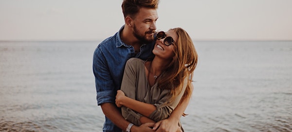 Modern couple on the beach hugging and loving each other