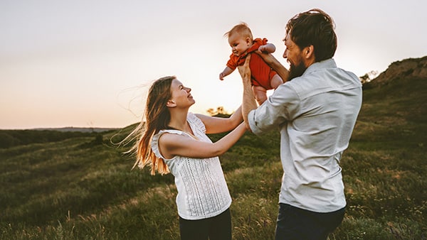 Happy family walking with infant baby outdoor.