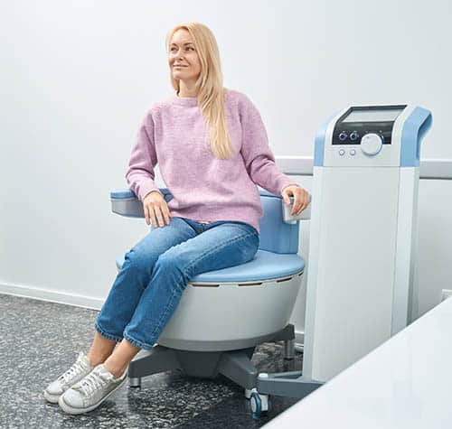 Adult woman using an emsella chair for pelvic floor strengthening.