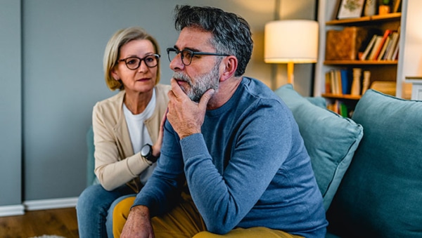 Mature woman comforting her worried husband at home
